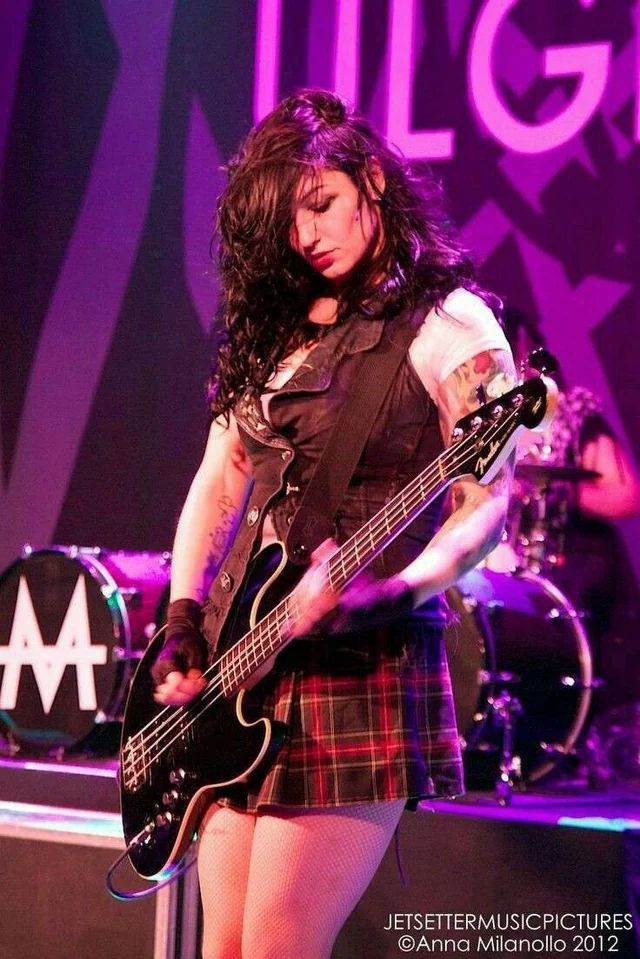 a woman in a skirt playing a guitar on stage