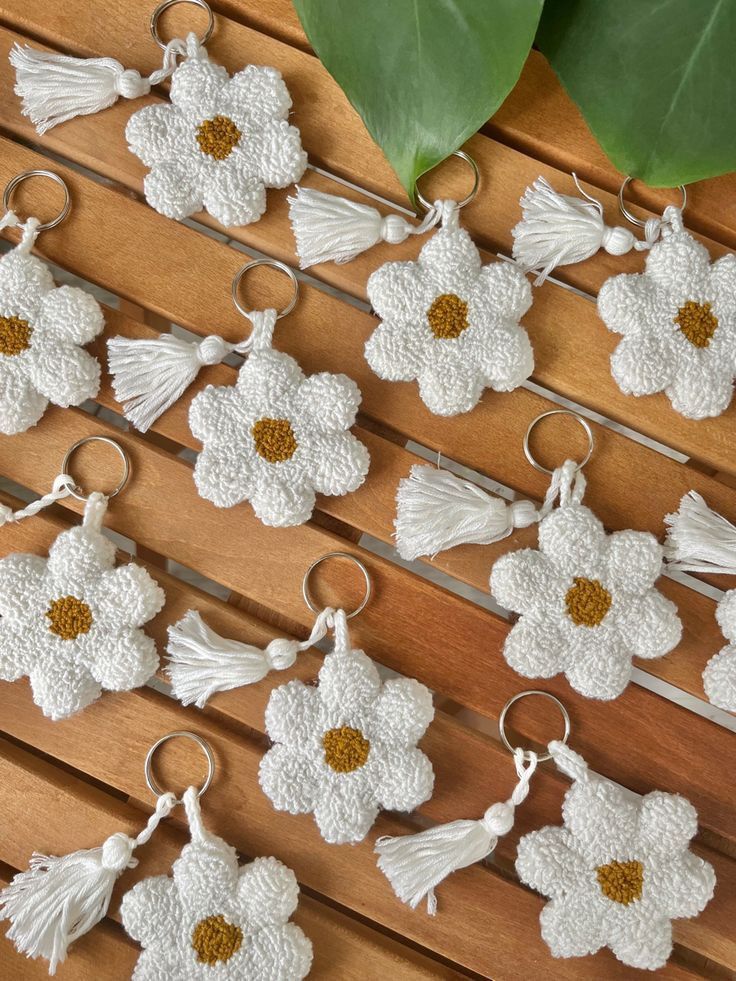 white crocheted keychains with tassels and flowers on wooden table