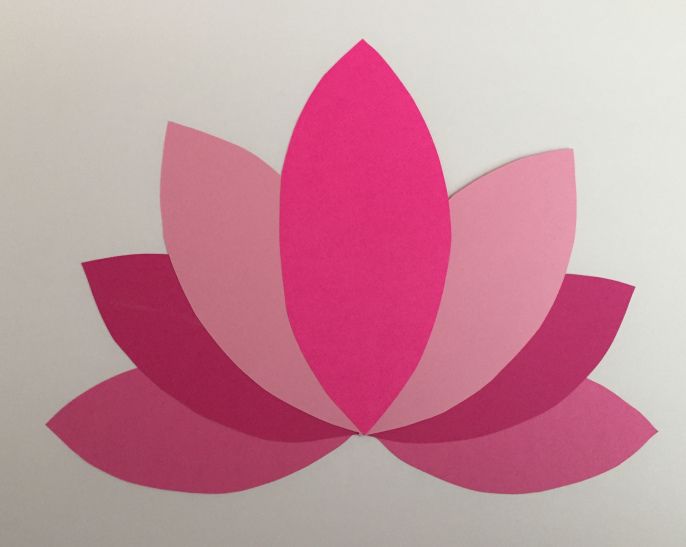 a pink flower cut out from paper on a white background with the words lotus written below it