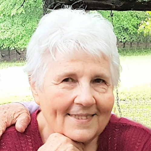 an older woman with white hair is smiling at the camera and holding her hand on her shoulder