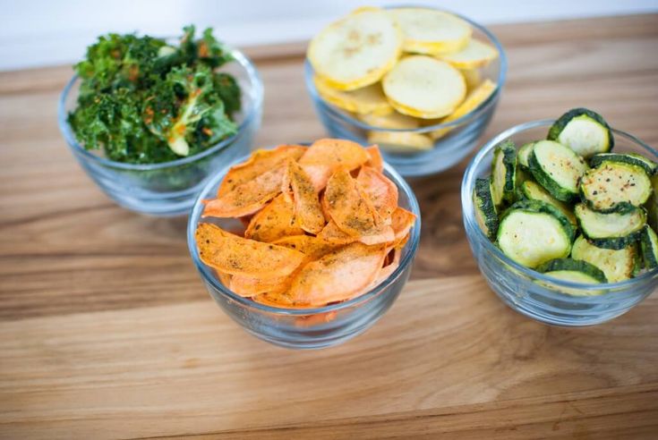 four bowls filled with different types of food on top of a wooden table next to each other