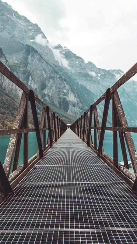 a long metal bridge with mountains in the background