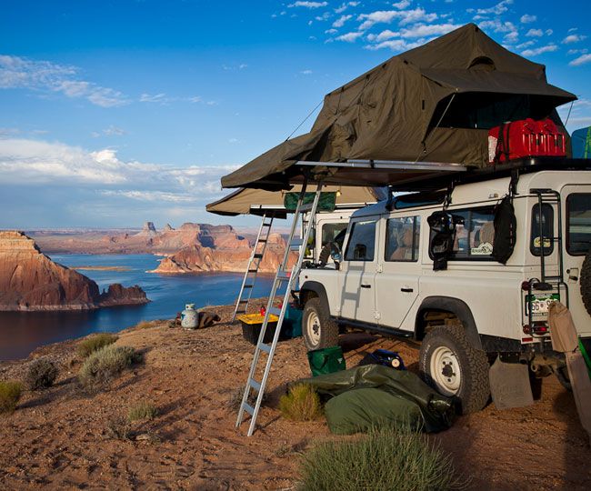 an suv parked on top of a hill next to a body of water and mountains