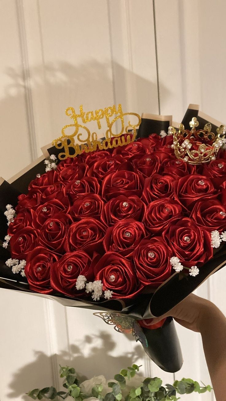 a woman holding a large bouquet of red roses with a happy birthday sign on top