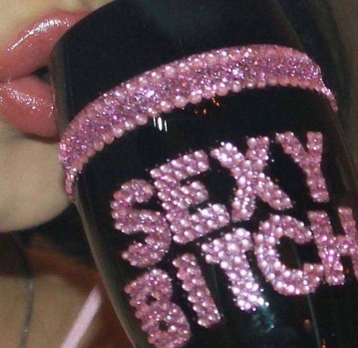 a close up of a person holding a black cup with pink glitters on it