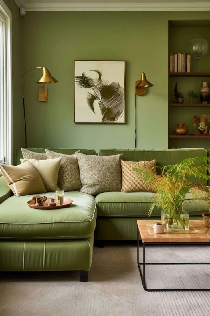 a living room with green walls and couches, coffee table and plants in the corner