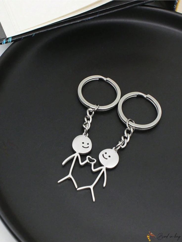 two metal key chains on top of a black plate