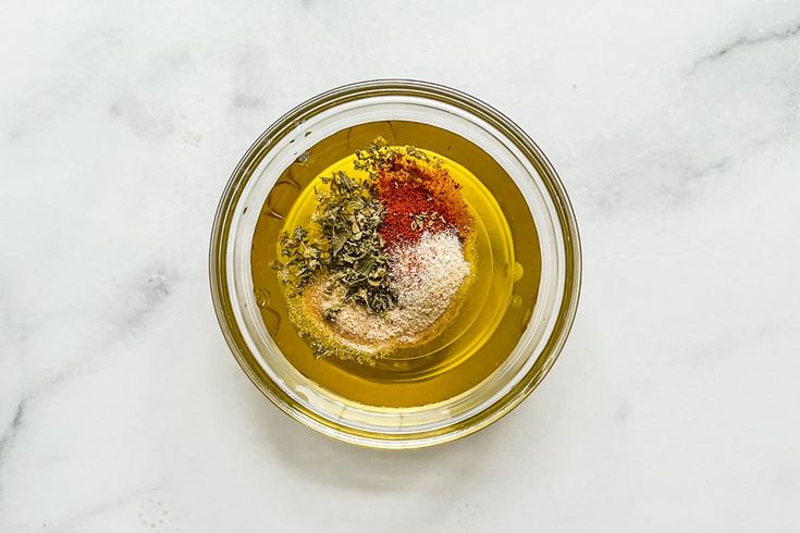 a glass bowl filled with spices on top of a white counter