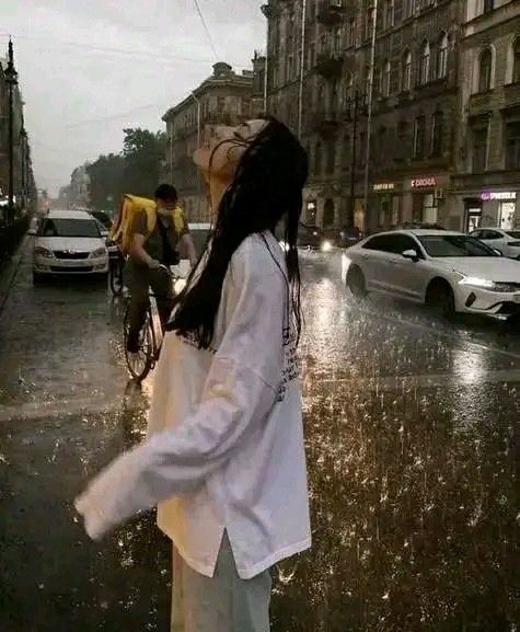 a woman standing in the rain next to a man on a bike