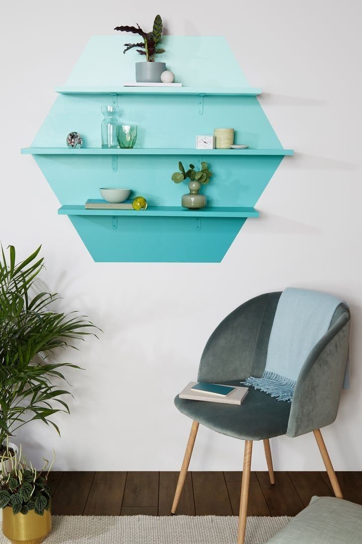 a room with a chair, potted plant and shelves on the wall