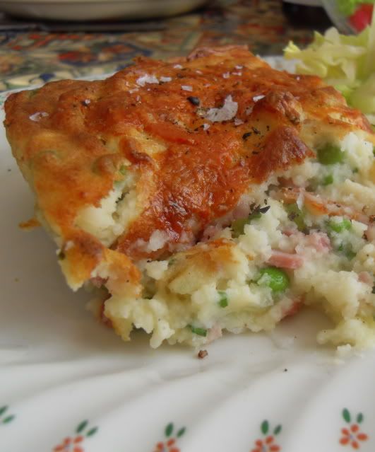 a close up of a piece of food on a plate with a salad in the background