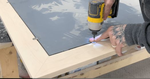 a man is using a drill to attach a piece of wood