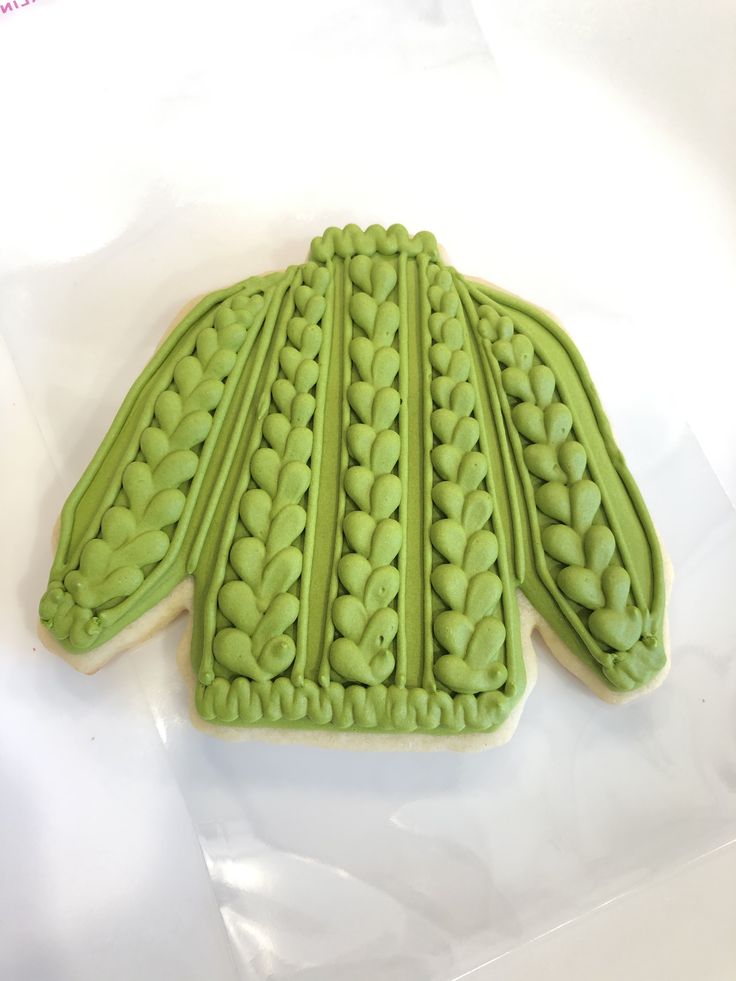 a cookie with green icing in the shape of a frilly pattern on it