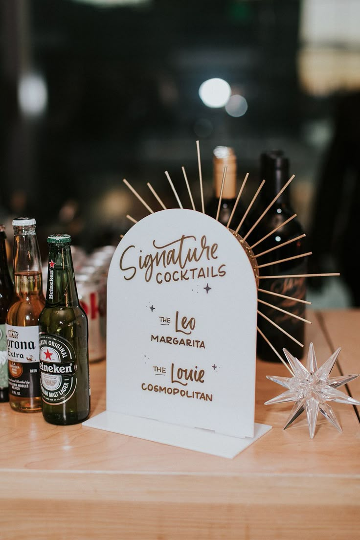 there is a sign that says signature cocktails next to some beer bottles on a table