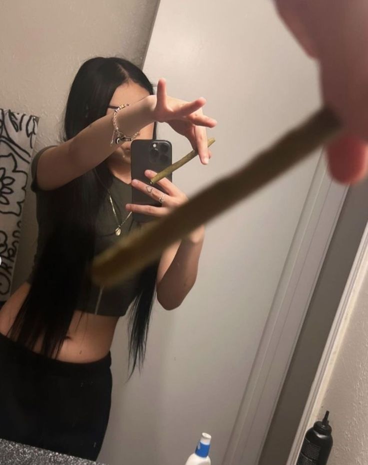 a woman taking a selfie in front of a mirror with a toothbrush sticking out of her mouth