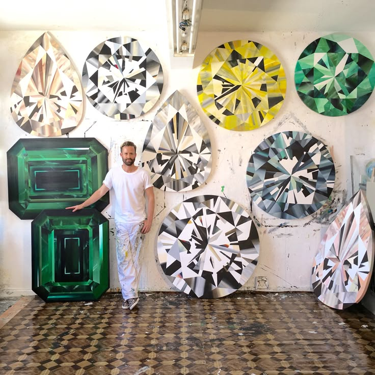 a man standing in front of a wall with lots of different colored discs on it