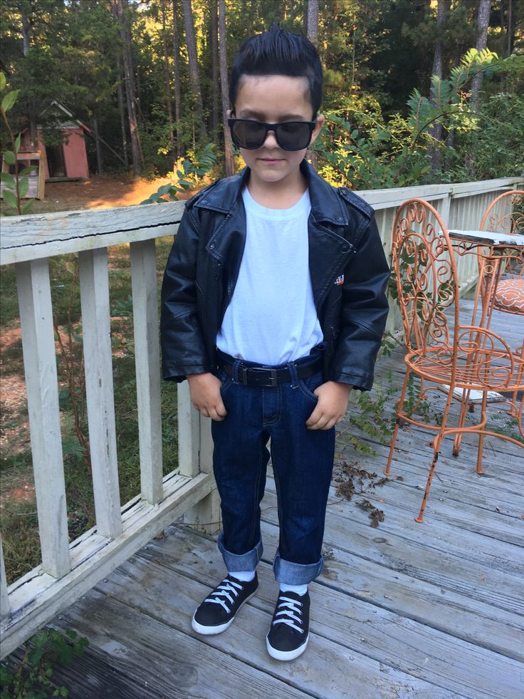 a young boy wearing sunglasses standing on a deck