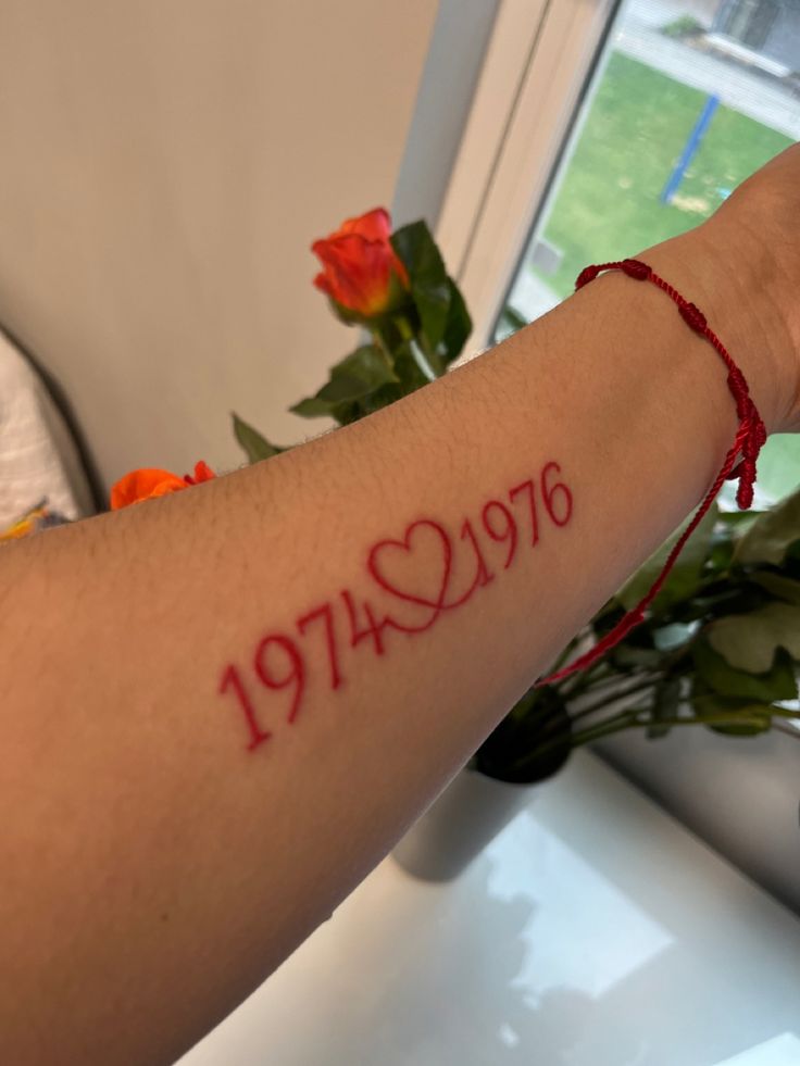 a woman's arm with the word love written on it and a red string around her wrist