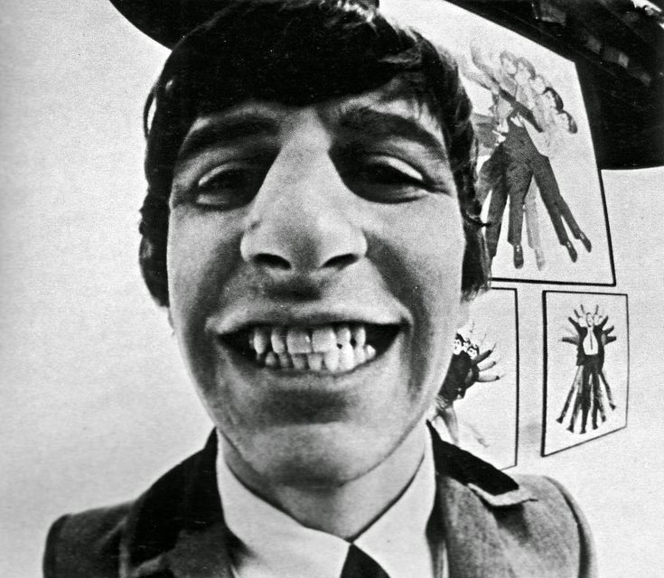 an old black and white photo of a young man wearing a hat with stickers on it