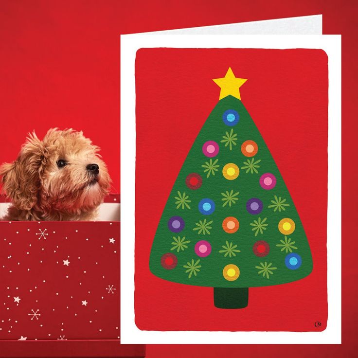 a small dog sitting in front of a christmas card with a tree on it's side