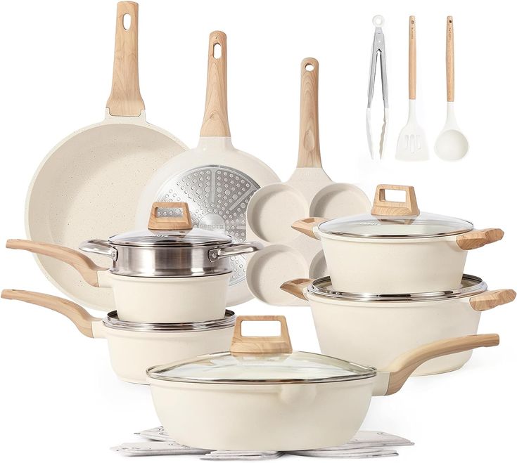 an assortment of white pots and pans with wooden spoons, spatulas and utensils