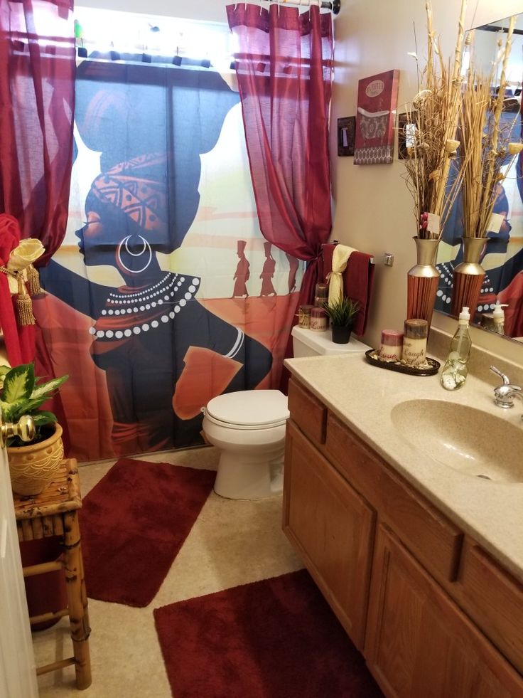 a bathroom decorated in african style with red curtains