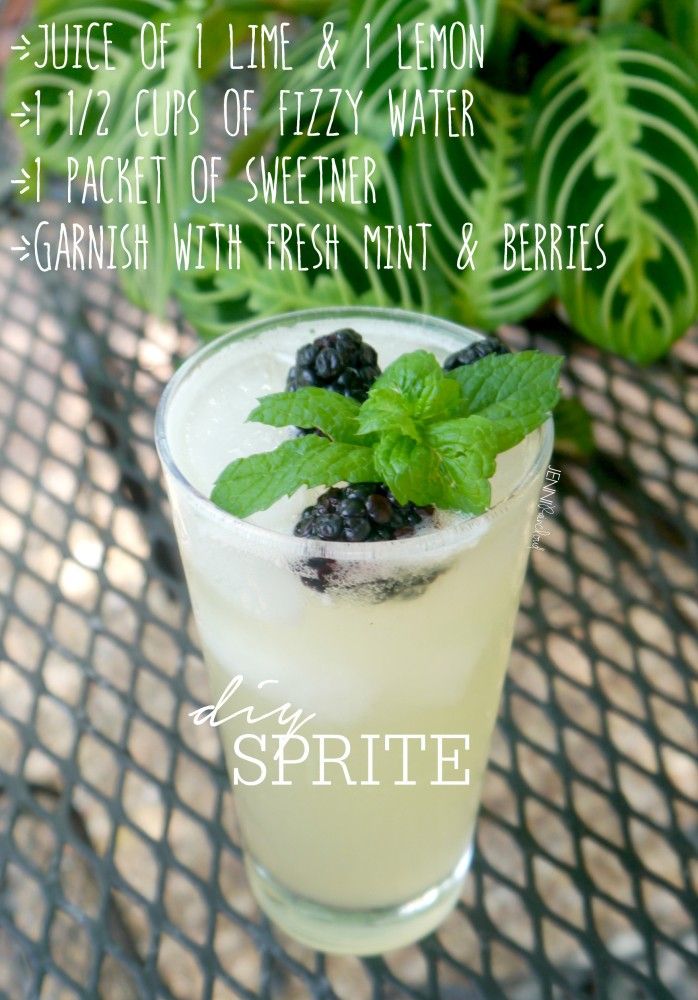 a glass filled with lemonade and blackberries on top of a table next to plants