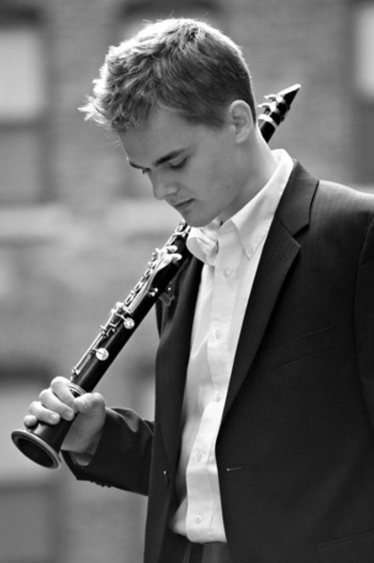 a young man in a tuxedo is holding a flute and looking at it