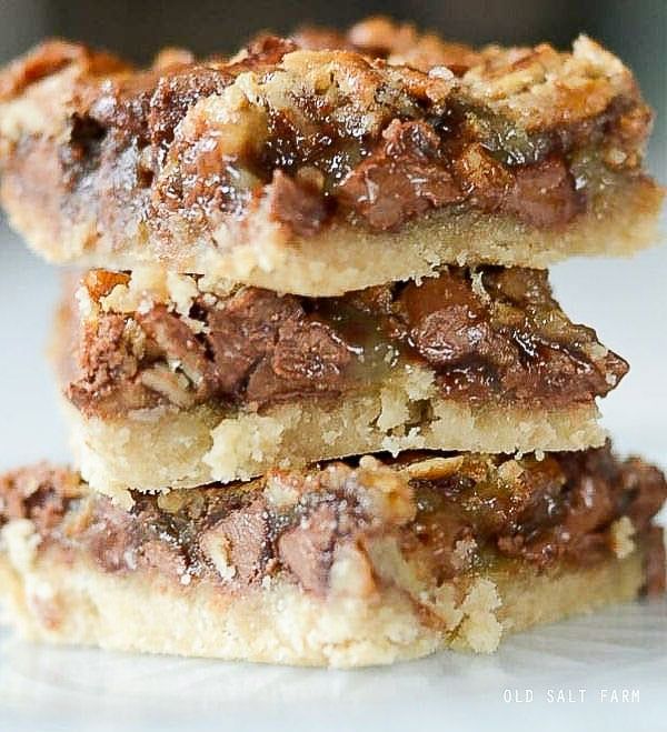 three pieces of chocolate pecan bars stacked on top of each other in front of the camera