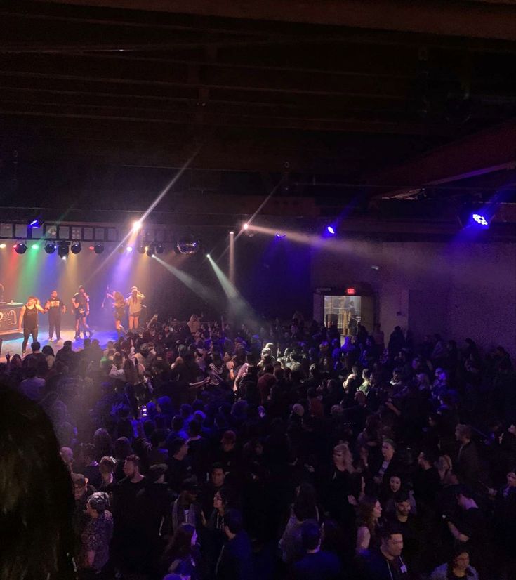 a group of people standing on top of a stage in front of purple and green lights