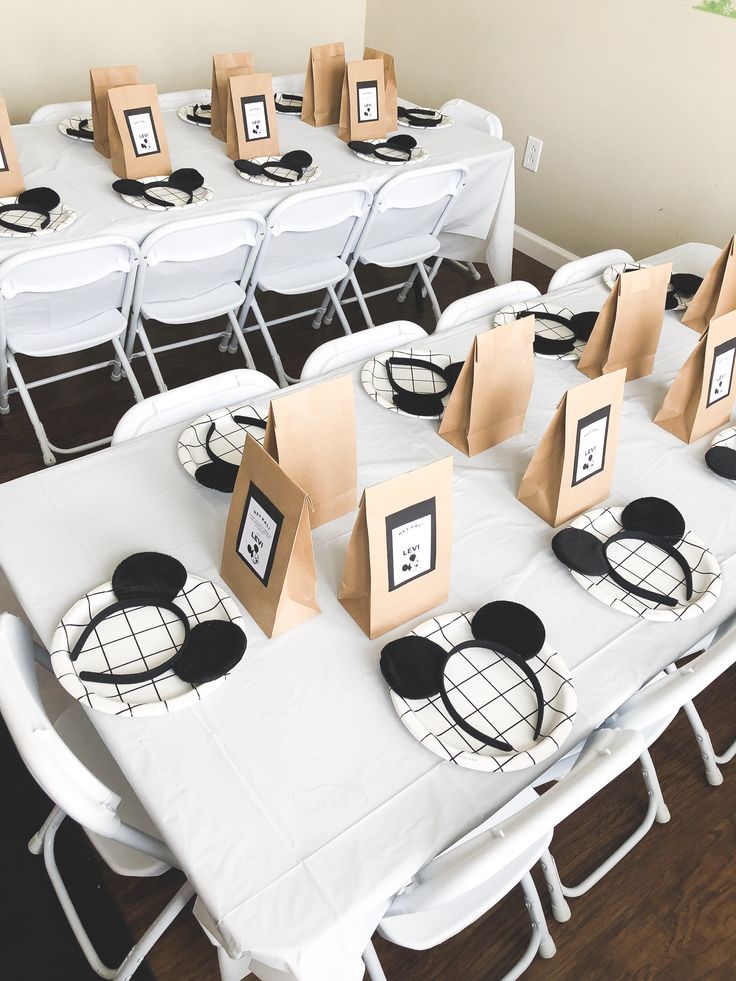 the table is set up for a mickey mouse themed party with paper bags and place cards