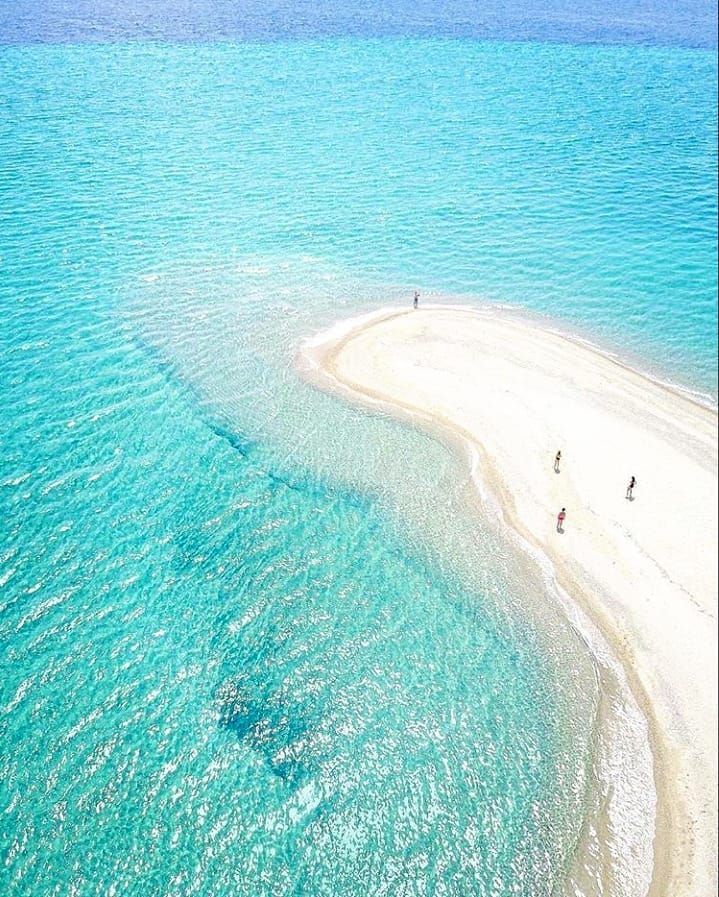 an aerial view of people walking on the beach and in the water near some sand