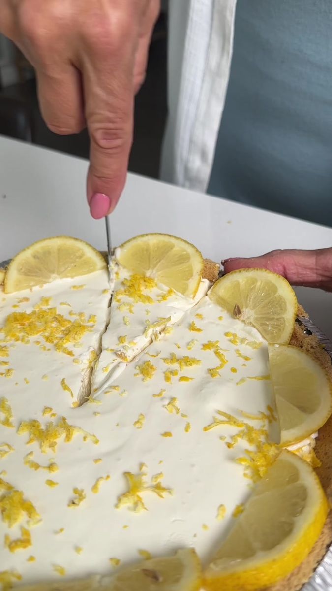 a person cutting into a lemon cake with a knife