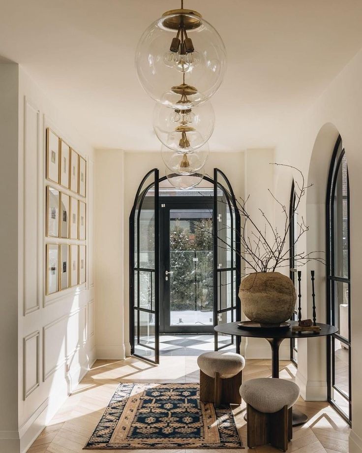 a hallway with an arched doorway and large glass doors leading to another room that has a rug on the floor