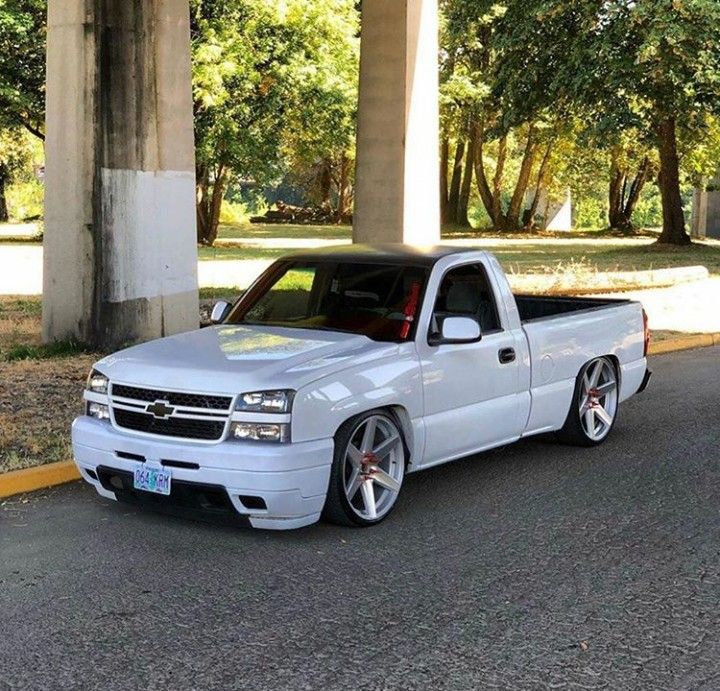 the white truck is parked on the side of the road near some pillars and trees