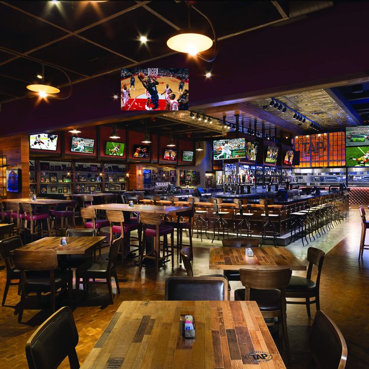 a sports themed bar with wooden tables and chairs