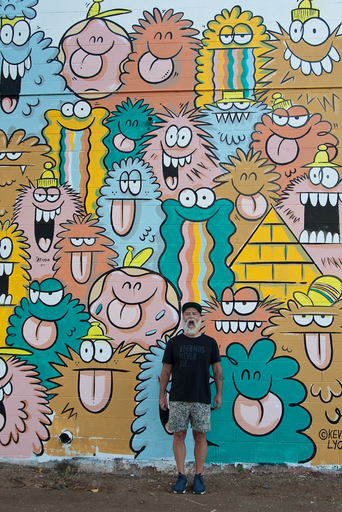 a man standing in front of a colorful wall with cartoon characters on it and smiling