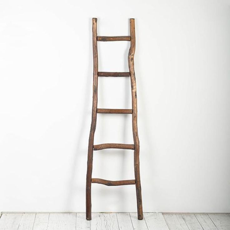 an old wooden ladder leaning against a white wall