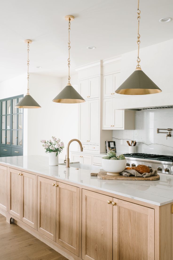 a kitchen with two lights hanging over the island and an oven in the back ground