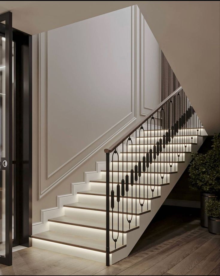 the stairs are lit up with white lights and black railings, along with potted plants