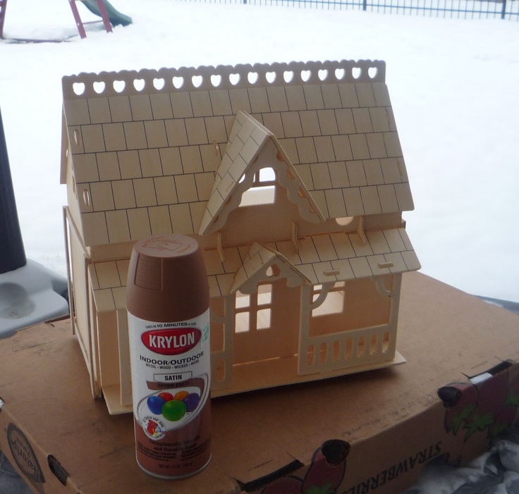 a wooden doll house sitting on top of a cardboard box next to a spray bottle