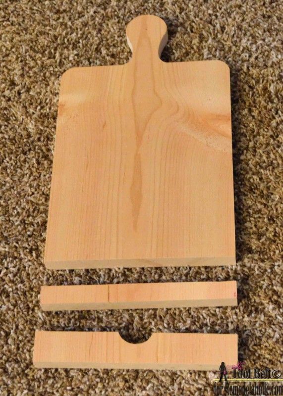 a wooden cutting board sitting on top of a carpeted floor next to a pair of scissors