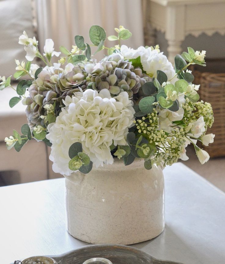 a white vase filled with lots of flowers on top of a table next to a tray