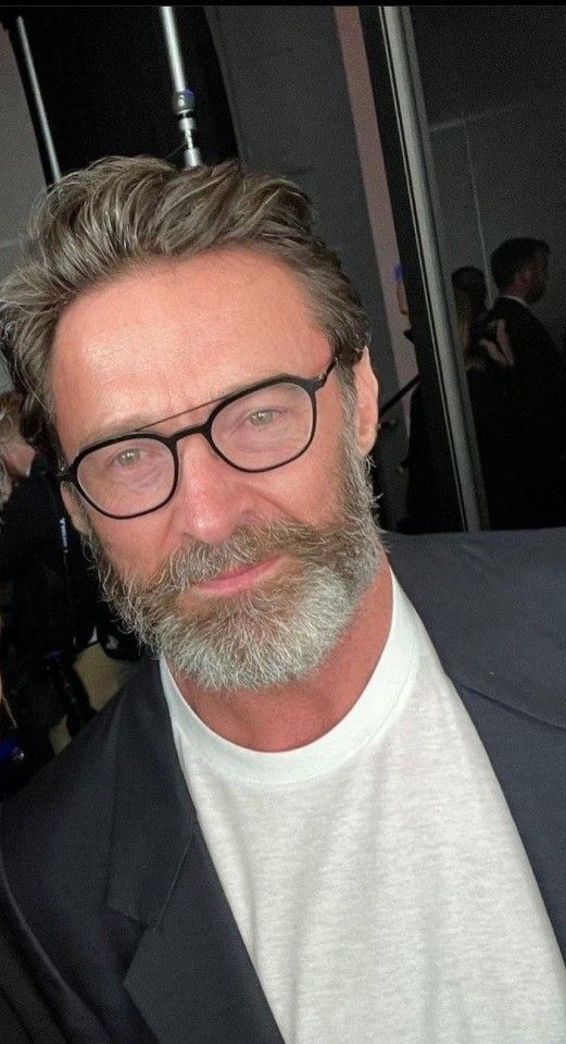 a man with glasses and a beard is smiling