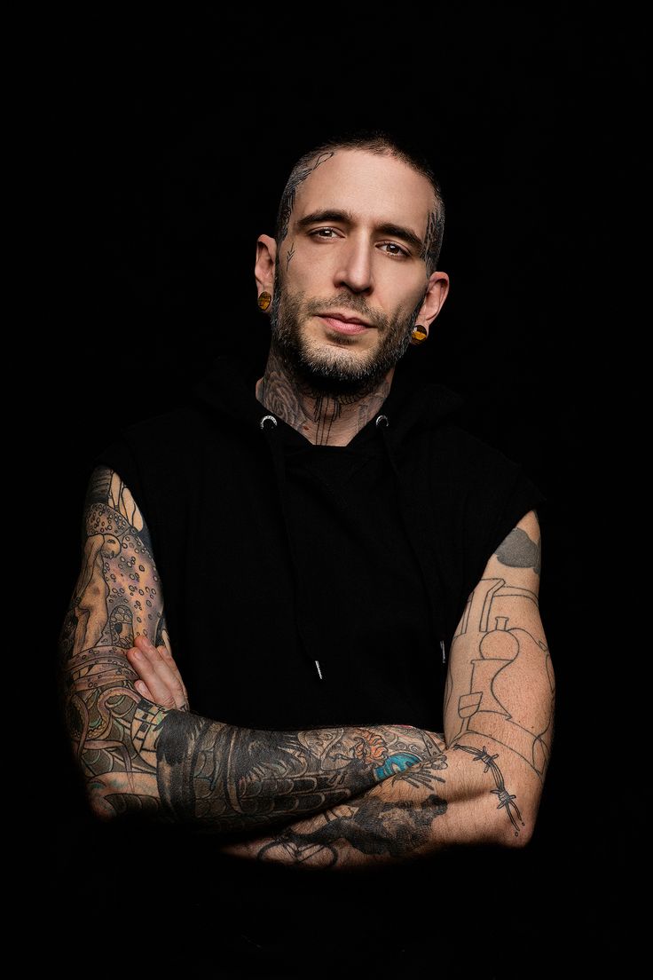 a man with tattoos and piercings on his arms is looking at the camera while posing for a photo