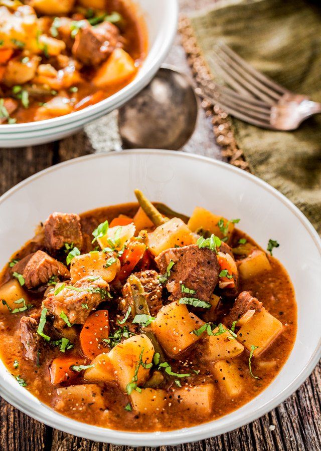 two white bowls filled with stew on top of a wooden table