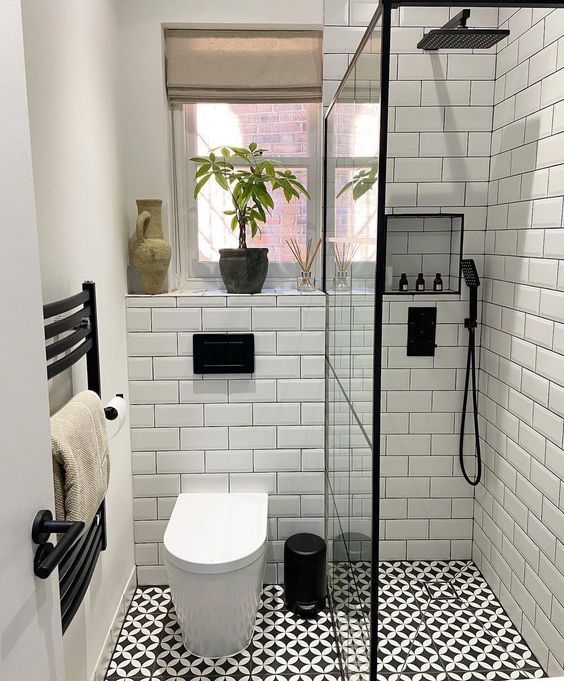 a black and white tiled bathroom with a toilet, shower head, and towel rack