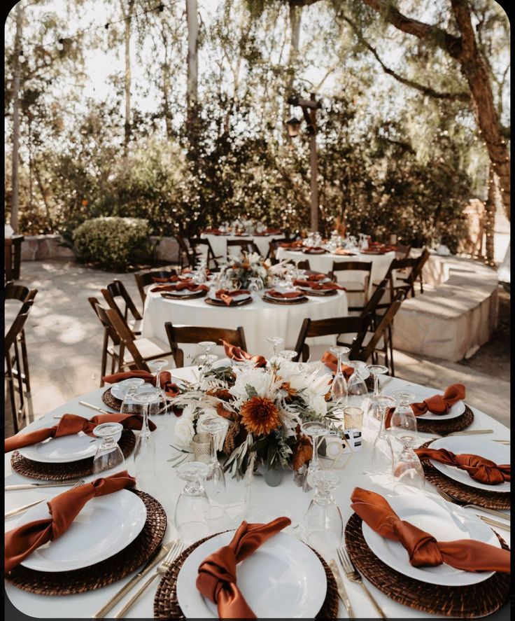 the table is set with white plates and orange napkins for an elegant wedding reception