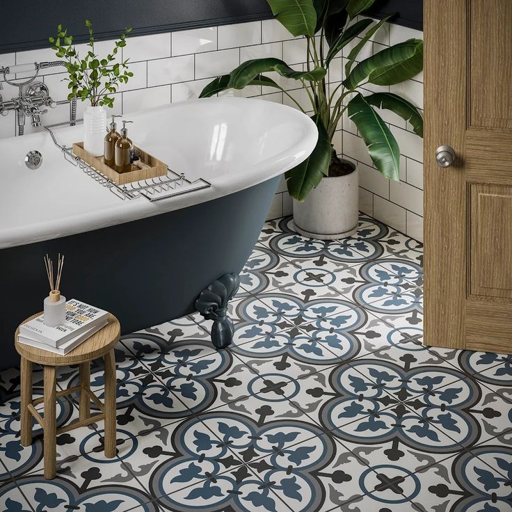 a bath tub sitting next to a wooden door in a bathroom with blue and white tiles on the floor