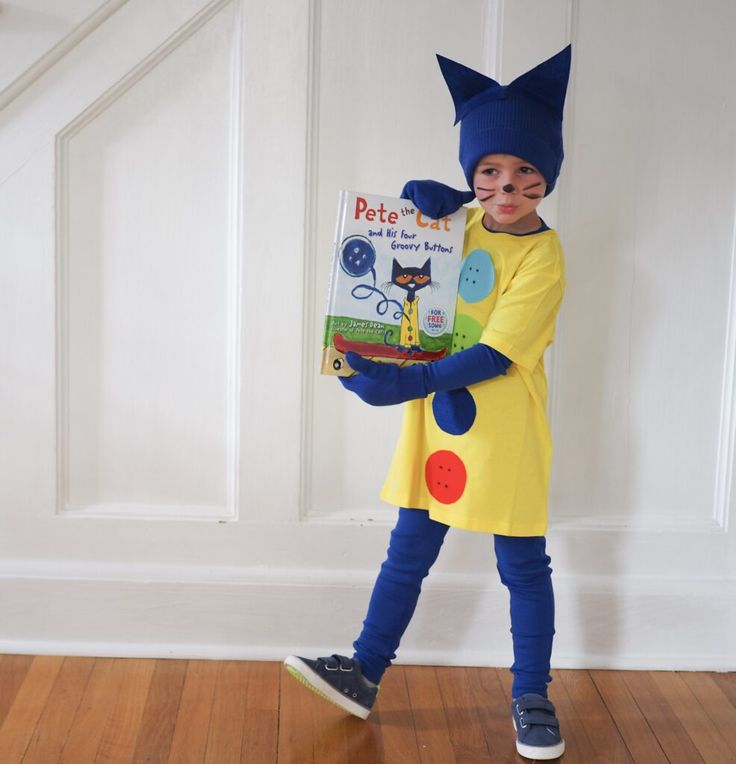 a little boy dressed up as pete the cat holding a book while standing on a hard wood floor